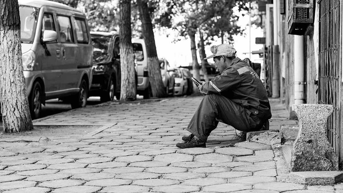 Un om se uită în telefon pe o stradă din Qingdao, China